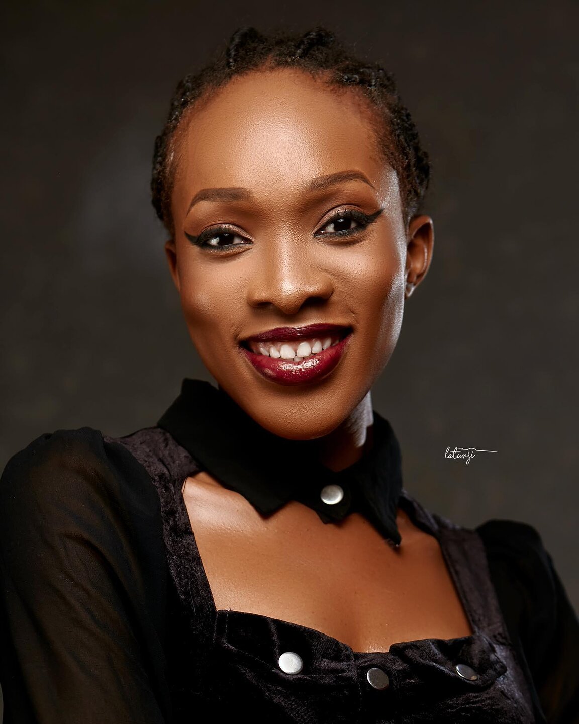 Smiling client with winged eyeliner, burgundy lips and braided hair